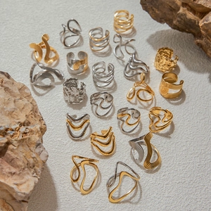 Assorted minimalist stainless steel rings in gold and silver finish on stone background