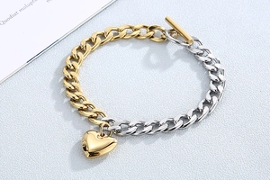Detail of two-tone gold and silver Cuban chain bracelet with heart pendant and T-bar clasp