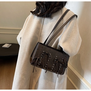 Detail of dark brown PU leather shoulder bag with woven accents and silver studs