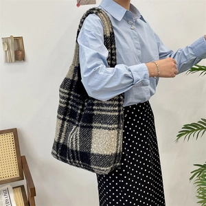 Close-up of black and white plaid wool tote bag showing thick fuzzy texture and shoulder strap
