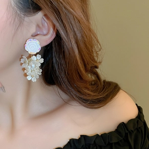 Detail of sweet floral drop earrings with iridescent white petals and golden stamen accents