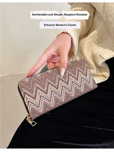 Detail of long zipper wallet with brown chevron pattern and gold hardware in hand