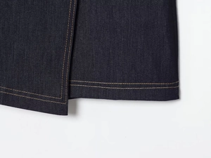 Gros plan détaillé de l'ourlet d'une veste en jean bleu marine avec coutures jaunes