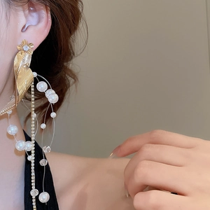 Close-up of dangling flower earrings with pearls and rhinestones worn by a model