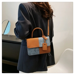Detail of color-block crossbody bag with brown leather, grey fabric, and fashion tag