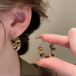 Detailed view of vintage gold earrings with brown tiger eye beads and pearl accents