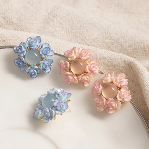 Detailed view of floral resin earrings with roses and translucent beads on white ceramic