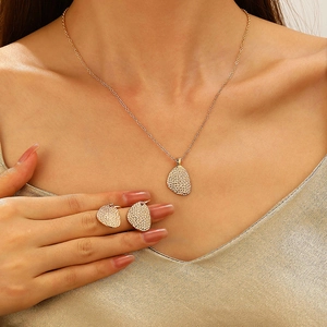 Close-up of gold shell-shaped necklace and earrings set with sparkling crystals on model