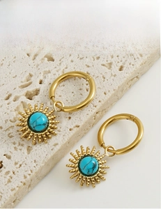 Detail of gold starburst earrings with turquoise stone inlay on natural stone base