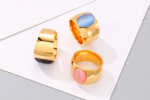 Drei goldene Titanringe mit ovalen Katzenaugen-Steinen in Blau, Pink und Tigerauge-Braun