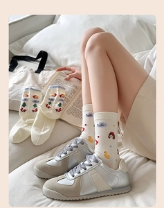 Détail des chaussettes en coton blanc cassé avec motifs animés et baskets rétro