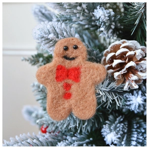 Macro shot of handcrafted wool felt gingerbread man ornament with red bow on Christmas tree