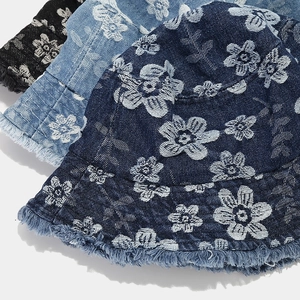 Close-up of denim bucket hats with floral patterns and frayed edges in three colors