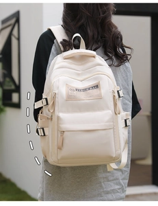 Detail of wide padded shoulder straps and multi-pocket structure on beige backpack