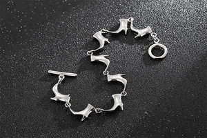 Détail d'un bracelet en acier avec breloques bottines et fermoir à bascule sur pierre