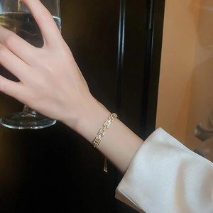 Détail du bracelet doré à maillons en H serti de cristaux sur le poignet d'une femme
