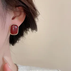 Detailed close-up of a vintage red agate earring with textured gold-tone metal frame