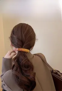 Detail view of a large amber marble resin hair clip worn on an elegant low ponytail
