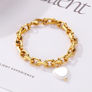 Detailaufnahme des goldenen Kettenglied-Armbands mit Herzanhänger aus Muschel auf Magazin