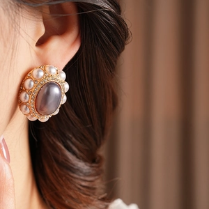 Macro detail of vintage style gold earrings with zircon crystals and oval purple pearls