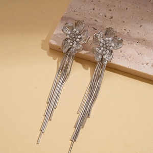Close-up of silver flower tassel earrings with pearls and crystals on stone