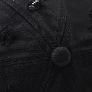 Macro shot of distressed cotton twill fabric and button detail on black baseball cap