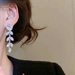 Macro side view of elegant silver floral tassel earrings with zircon crystals on a model