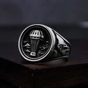 Retro stainless steel ring with parachute relief and skull side details on wood base