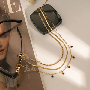Detailed view of triple-layered gold necklaces with black gemstone charms on Vogue magazine