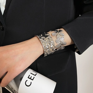 Detail of silver textured hammer cuff and openwork flower bracelet set on wrist