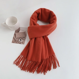 Minimalist red cashmere-feel tassel scarf neatly folded on a white surface with lifestyle props