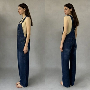 Detail of adjustable metal buckles and deep blue denim fabric on women's loose overalls