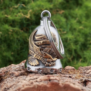 Detailed close-up of eagle bell pendant in silver and bronze on natural wood
