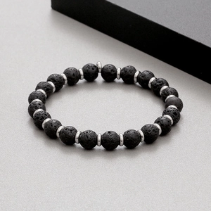 Close-up of black porous lava stone beads with steel spacer discs on a beaded bracelet
