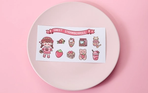 Close-up of pink strawberry girl and bear stickers on a pastel tray for planners