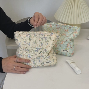 Detailed close-up of floral canvas toiletry bags in cream and light green colors