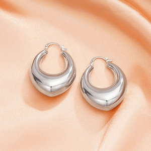 Close-up of polished silver U-shaped hoop earrings on elegant silk fabric background