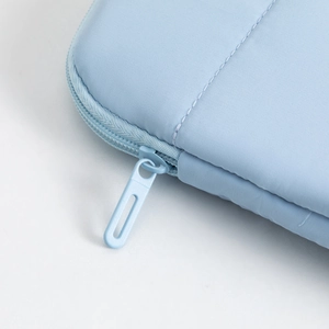 Macro detail of high-quality light blue laptop sleeve featuring smooth matte zipper hardware