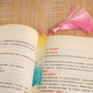 Macro shot of DIY resin bookmark with golden blue glitter and a pink silk tassel