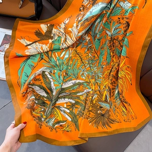 Detail of vibrant orange square scarf featuring tropical giraffes and jungle prints