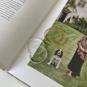Classic gold and silver twisted rope hoop earrings displayed on a vintage book page