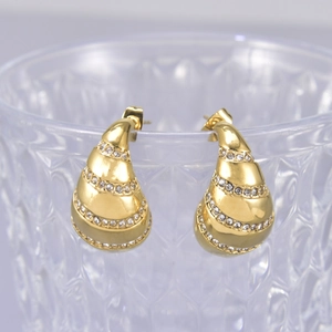 Elegant gold teardrop earrings with crystals hanging on a clear glass edge