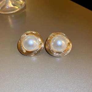 Vintage pearl stud earrings with golden spiral metal texture in a minimalist setup