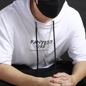 Close-up of vintage silver piano pendant necklace on model wearing white hoodie