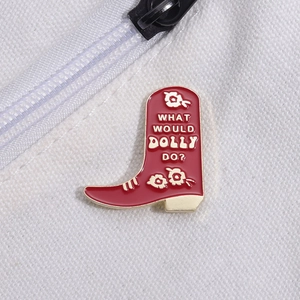 Red cowboy boot enamel pin with What Would Dolly Do text pinned on white canvas bag