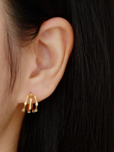 Close-up of three-row gold S925 silver earrings with sparkling cubic zirconia on model