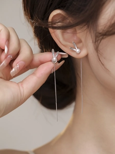 Detail shot of a silver bunny ear wire with white pearl and long tassel chains on model