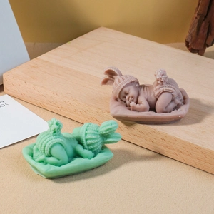 Detail of sleeping baby candle with intricate knit texture in green and pink hues