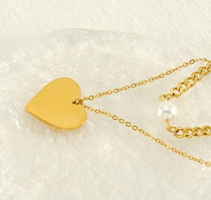 Detail of double-layer heart pendant necklace with white pearl on golden chain