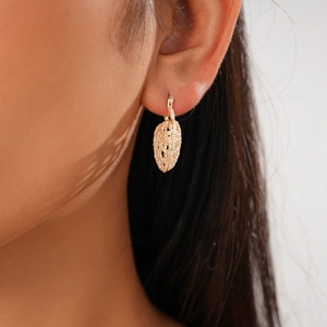 Close-up of golden hollow woven texture earrings worn by a model in a macro shot
